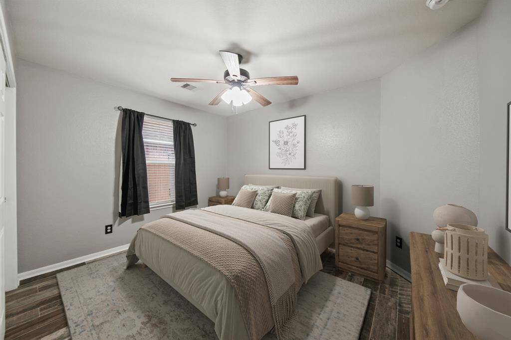 The third bedroom has a ceiling fan with light fixture, window with blinds & drapes overlooking the side yard and hardwood tile floors.