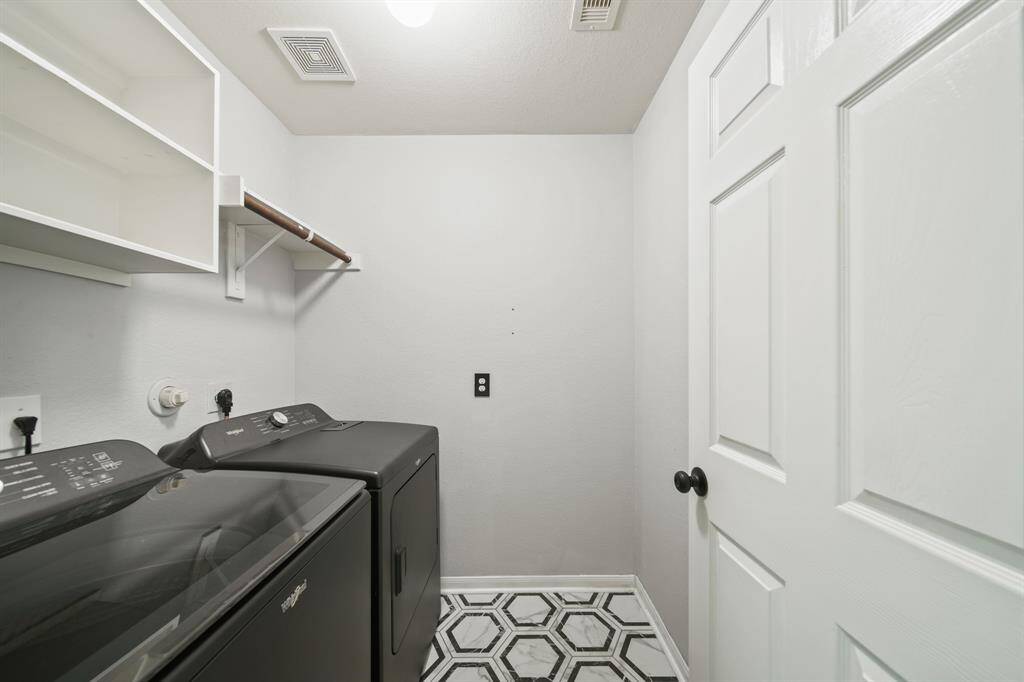 The utility room has upper shelf & hanging wardrobe storage space along with a natural gas dryer connection and tile flooring installed in 2023. Move in ready, this home includes a Whirlpool full size washer & dryer.