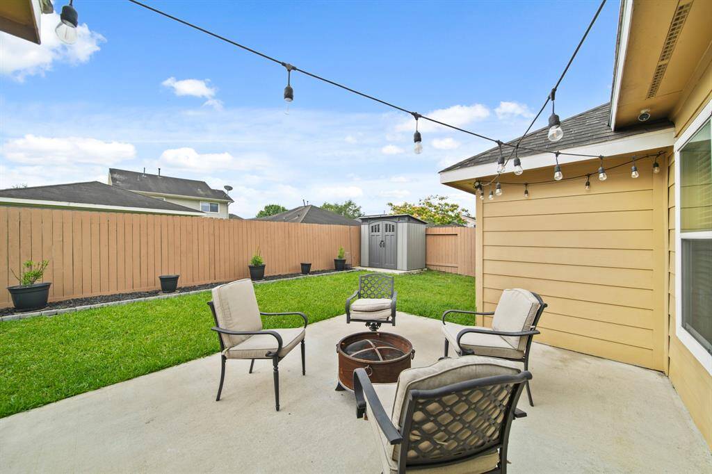 A view of the backyard from the patio illuminated by string lighting.