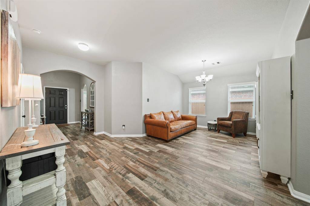 Currently serving as a sitting area, the formal dining room features chandelier lighting, windows with blinds overlooking the side yard & gleaming hardwood tile floors.