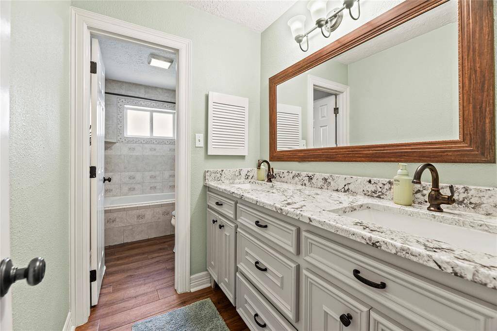 Updated guest bathroom with a dual sink granite vanity and tub/shower combination.