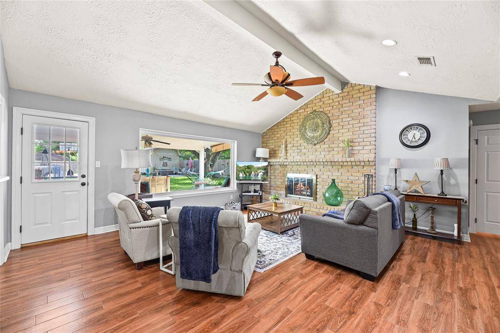 Spacious family room offers a vaulted ceiling and one of two fireplaces with brick surround.