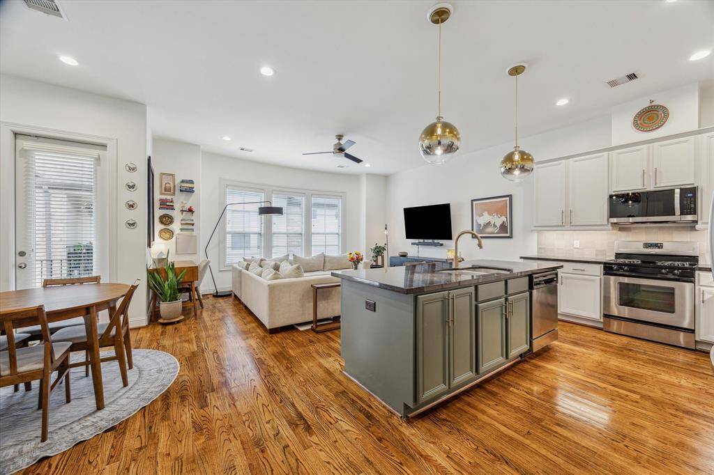 This spacious living area features neutral window coverings and warm hardwood flooring, creating a cozy and inviting atmosphere. Recessed LED lighting adds a modern touch, while the open layout seamlessly connects to the kitchen and breakfast room, perfect for entertaining and everyday living.