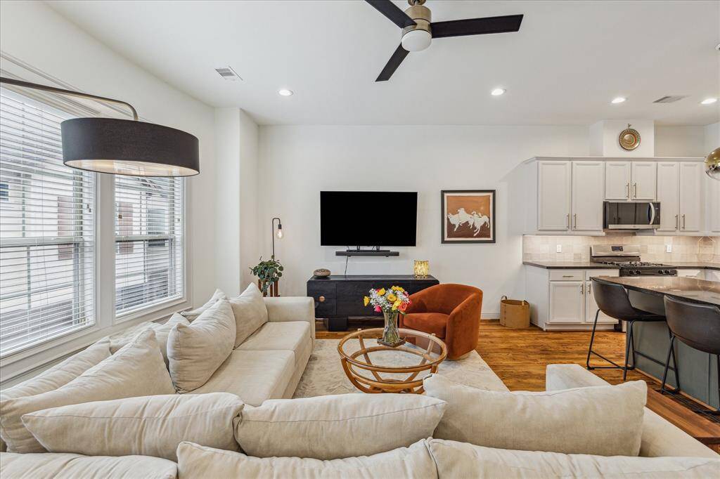 This living room features a sleek matte black ceiling fan that adds a modern touch. Neutral window coverings complete the space, offering a clean and versatile look.