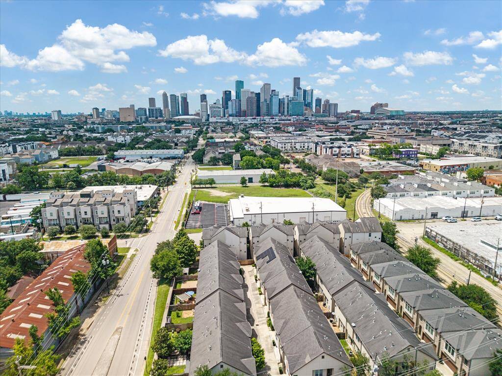 Aerial view of a serene private community nestled in lush greenery, with the towering Houston skyline providing a striking urban backdrop.