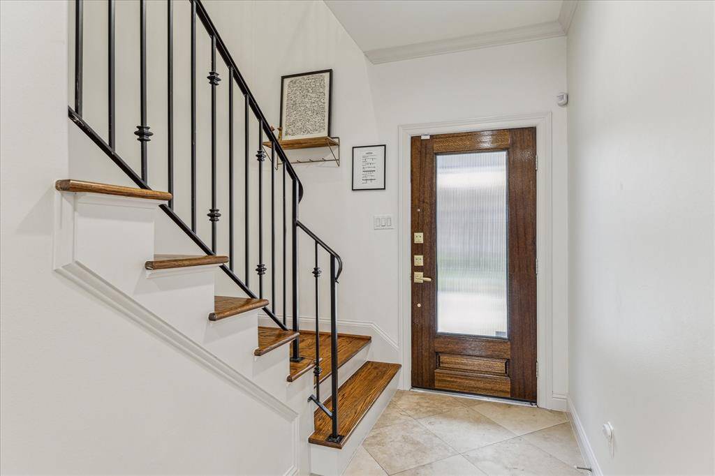 The inviting entry features neutral designer wall paint and tile flooring, offering easy access to the garage, staircase, study/secondary bedroom, and guest bedroom. This functional layout enhances both style and convenience as you enter the home.