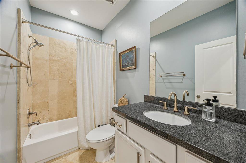 This stylish secondary bathroom features soft-close cabinetry and a sleek champagne bronze faucet. The tub/shower combo is complemented by granite countertops and an under-mount white sink, creating a modern and functional space. The elegant finishes add both beauty and convenience to the room.