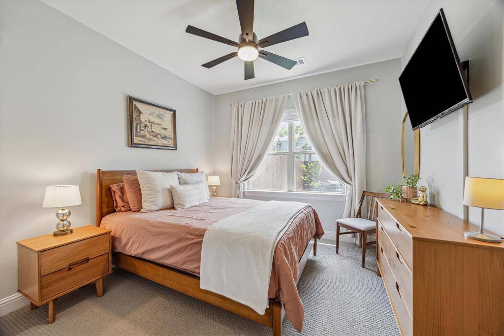 This inviting secondary bedroom, located on the first floor, features a window with southern exposures that fill the room with natural light. A modern matte black ceiling fan adds both style and comfort to the space. It’s a perfect retreat with a bright and airy atmosphere.