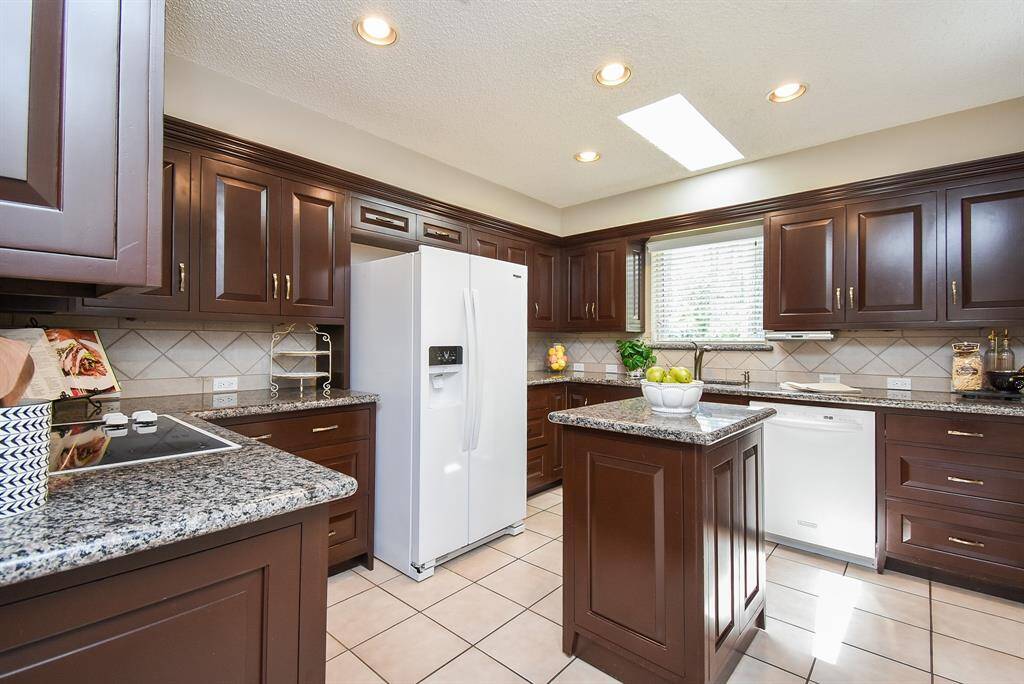 Rich chocolate colored cabinetry is everywhere, up, down, and around, just where you need it to be! Creamy granite countertops and light tile backsplash add contrasting hues to this truly workable kitchen.