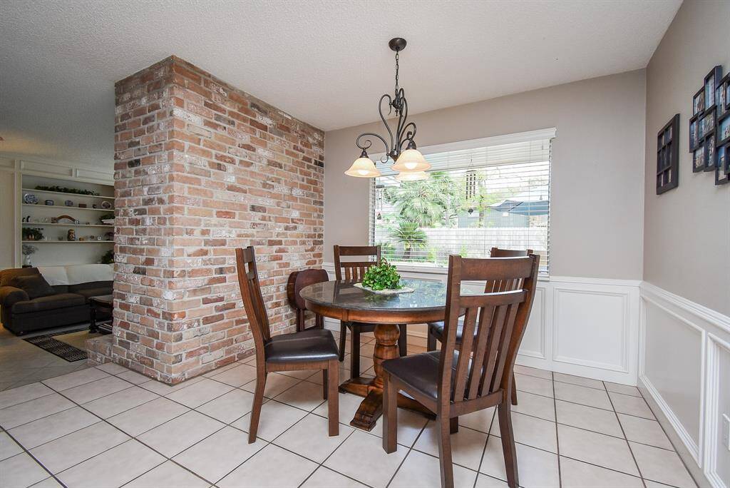 The brick wall/room divider adds a cozy vibe to both the breakfast nook on the kitchen side, and, of course, the fireplace on the living area side.