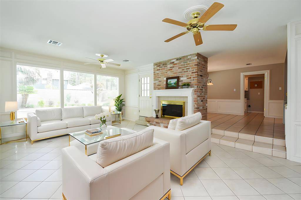 Even in 1973, at the time of the home's construction, wide open, airy space was offered in an open plan design. Pale walls greet luscious tile flooring in a generous living space, with high ceiling, a wall of windows, built-in brick wood burning fireplace, and tons of wall/floor space to imprint your lifestyle expressions.