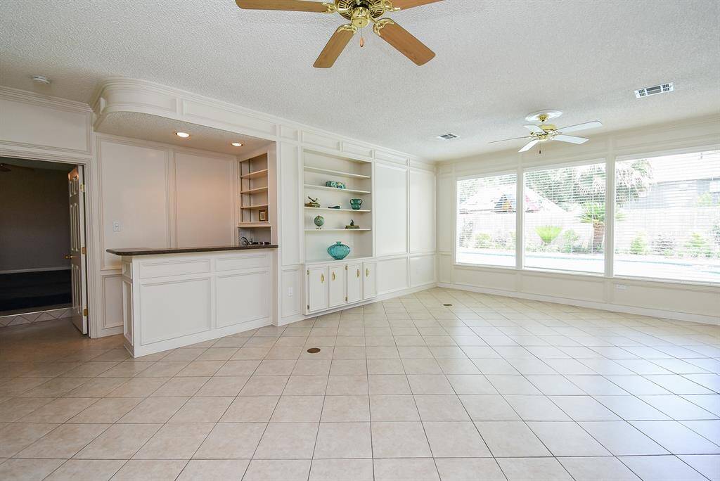 This amazing. forward thinking living area hosts built-in cabinetry space off the huge tile floor, warmed by a wall of picture windows.