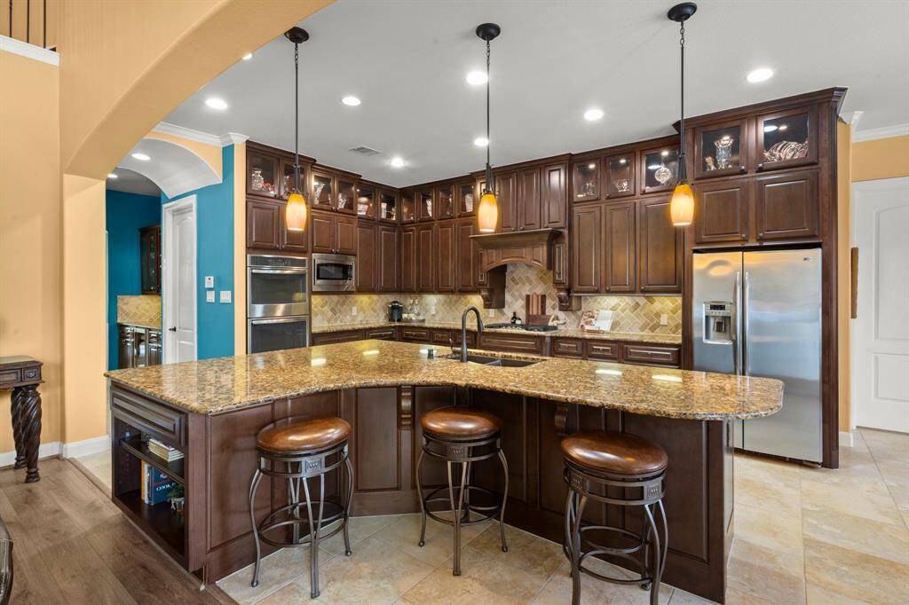 Statement piano-shaped island at the heart of the chef’s kitchen, 5-burner cooktop, double ovens, hidden spice racks & more!