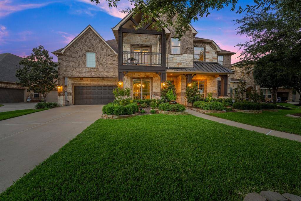 Beautiful brick, stone and wood-accented porch with charming landscaping.