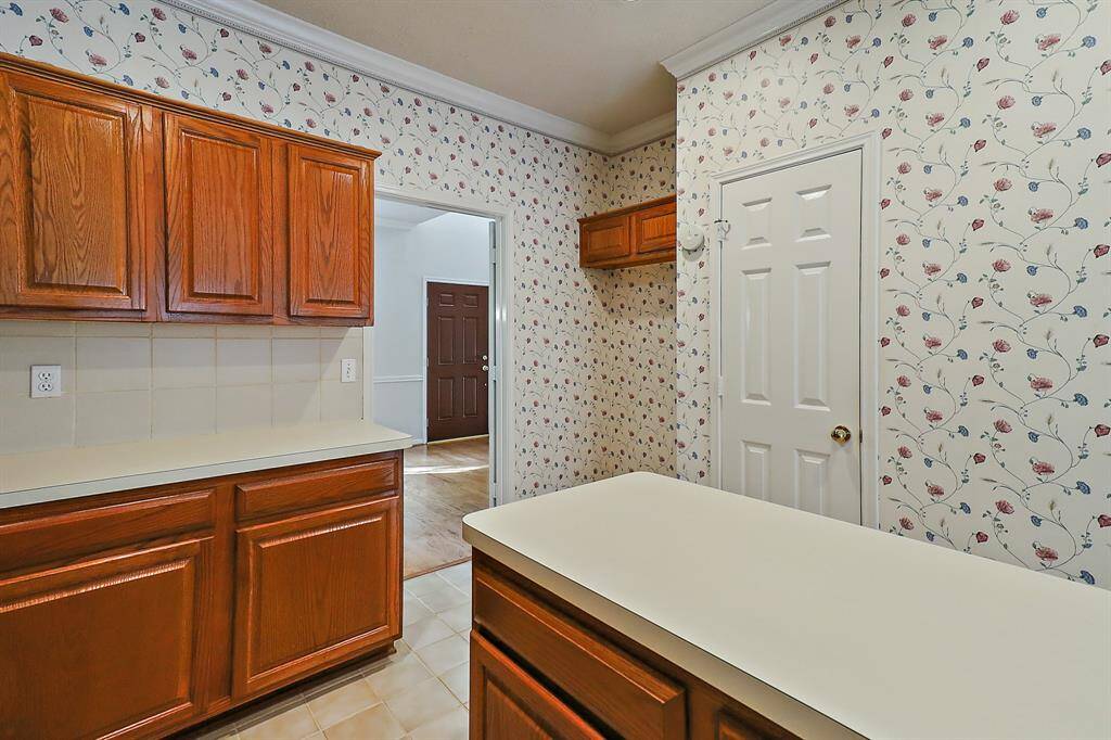 Cozy kitchen featuring warm wood cabinetry and charming floral wallpaper, perfect for culinary creativity.