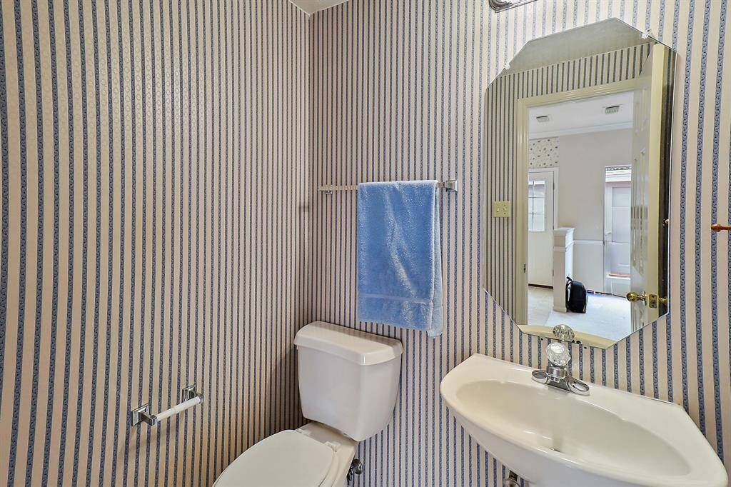 Convenient downstairs half bath with stylish striped wallpaper.