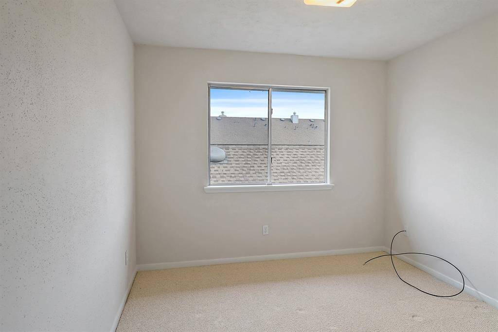 Cozy secondary bedroom with ample natural light from a large window. Ideal for guests or a home office.