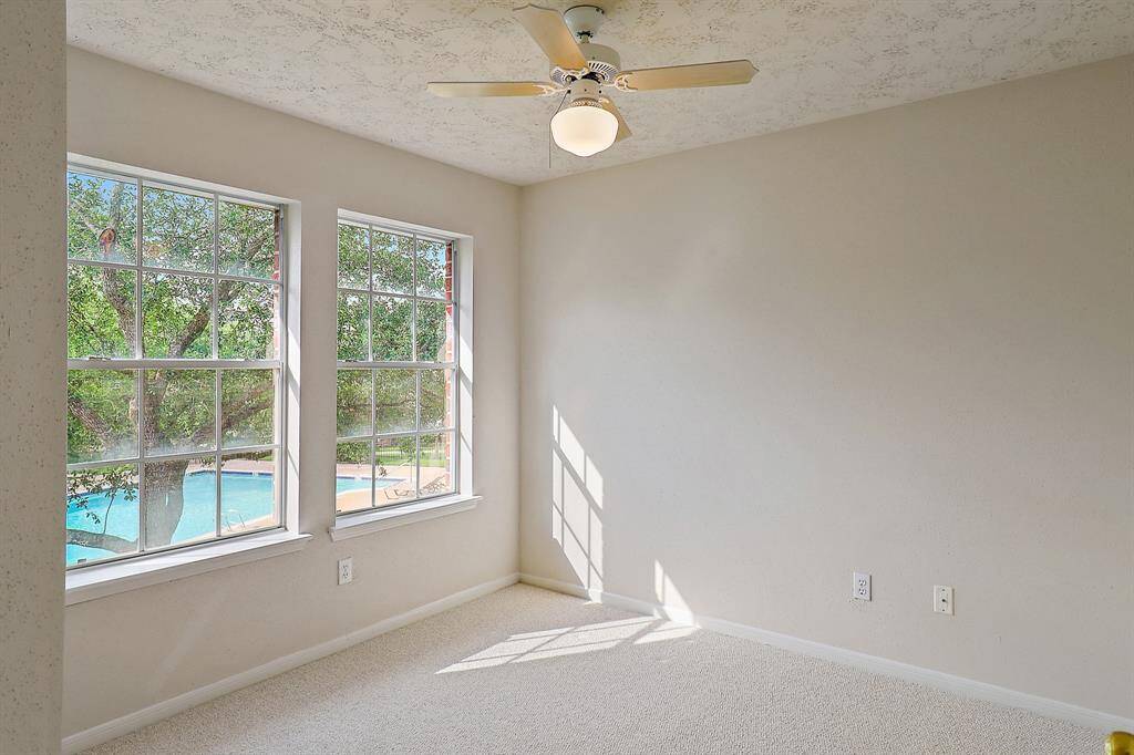 Bright upstairs bedroom with serene views of the community pool.