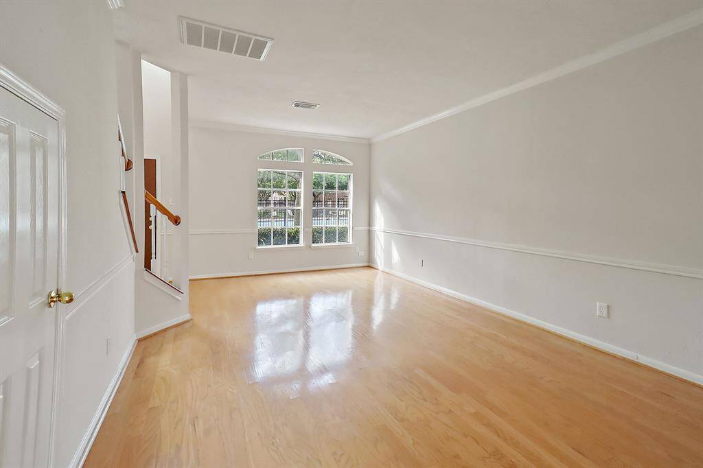 Bright and inviting living area with large windows and beautiful hardwood floors, perfect for relaxation and entertaining.