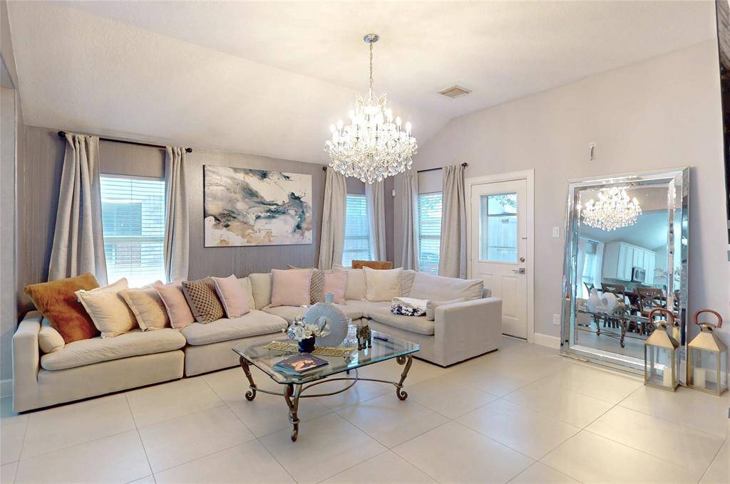 This elegant living room features a spacious, light-filled area. Neutral tones and a sleek tile floor create a welcoming atmosphere.