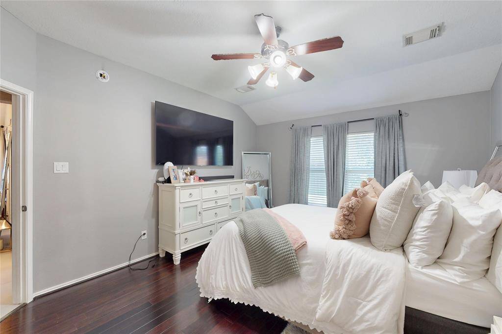 This primary bedroom includes a ceiling fan and windows with curtains providing natural light. It has an ensuite for comfort and convenience.