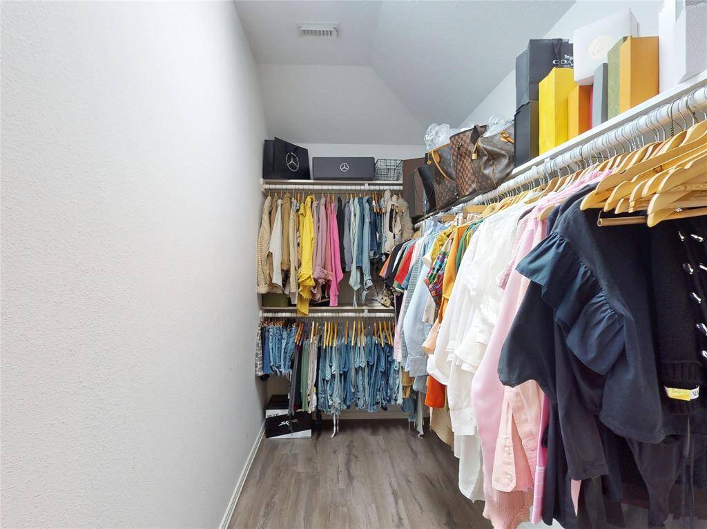 Spacious walk-in closet with hanging space, organized shelves, and stylish storage options, ideal for fashion enthusiasts. It has a separate water closet for privacy.