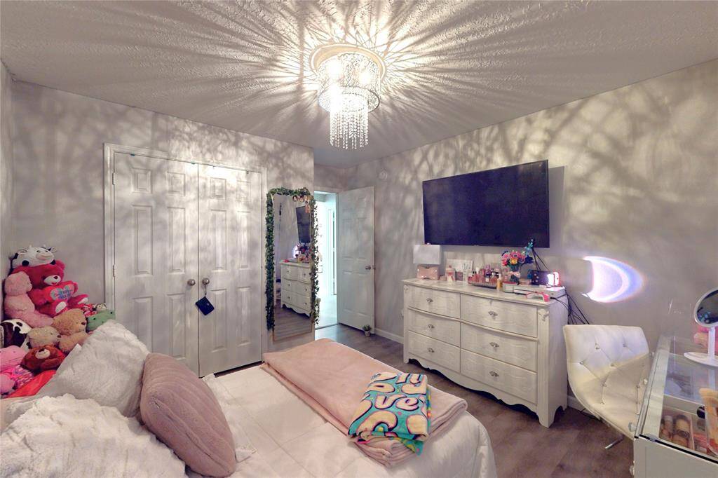 This cozy bedroom features a modern chandelier casting unique patterns on the ceiling, There's storage with a closet for functionality.