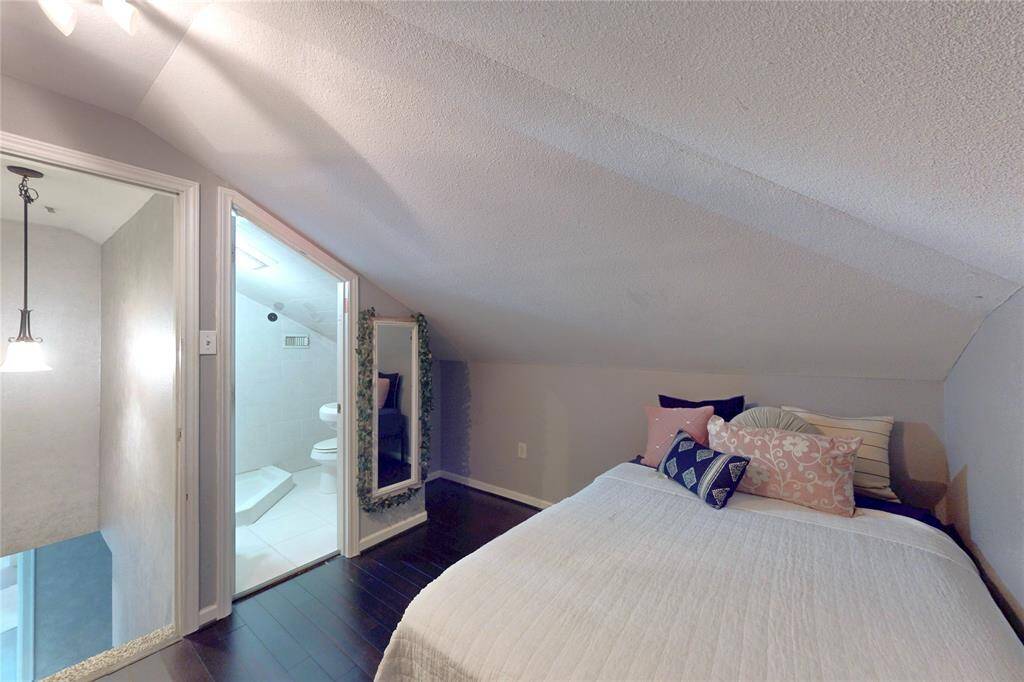 This cozy bedroom features a sloped ceiling, dark wood flooring. It includes an en-suite bathroom with a modern shower offering a compact and functional space.This space is currently being used as a beddroom but could provide an added work office space or gameroom etc. There are infinite possibilities for the use of this space.