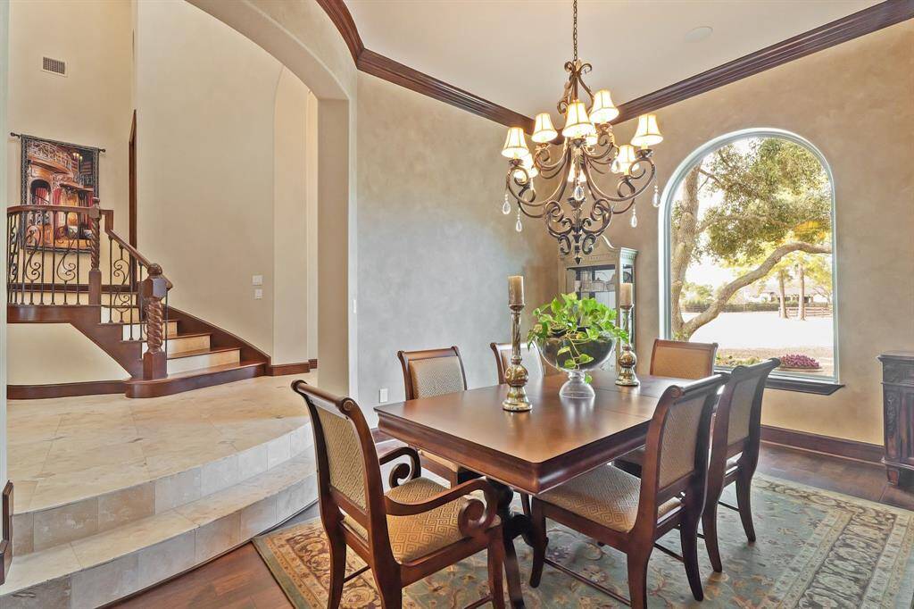 This Formal Dining Room boasts crown molding, gleaming hardwood floors, and a stunning chandelier, making it ideal for both intimate dinners and grand gatherings.