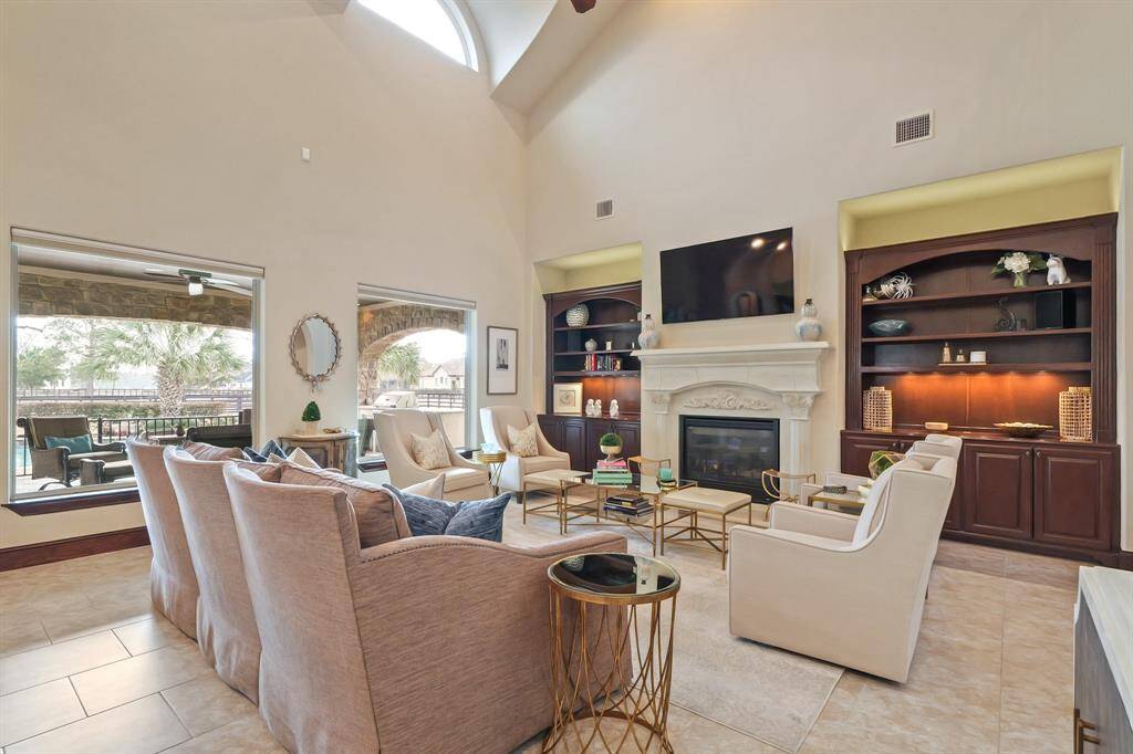 The Family Room features custom built-ins, a cozy Fireplace, and large windows with automatic remote controlled blinds that overlook the backyard oasis, creating a bright and inviting space perfect for relaxation and entertainment.