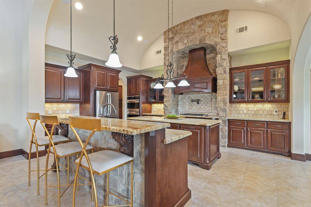 The spacious Kitchen boasts a Breakfast Bar, a stylish vent hood, and a pot filler above the stove, providing both style and convenience, perfect for cooking and entertaining."
