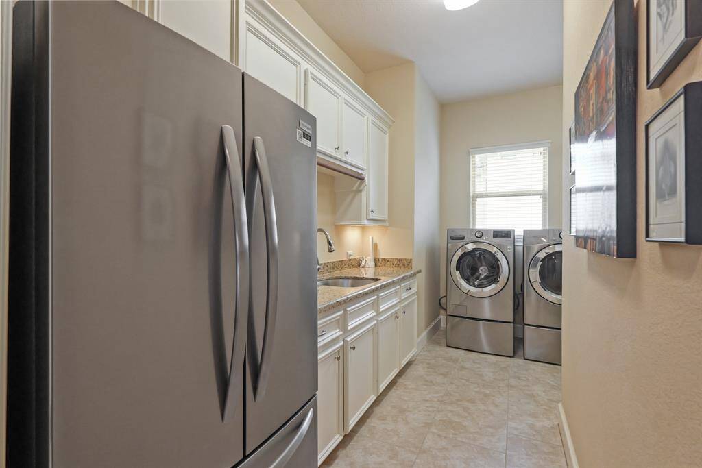 This large Utility Room offers abundant counter space and cabinetry, making it perfect for organizing household essentials and completing laundry tasks with ease.