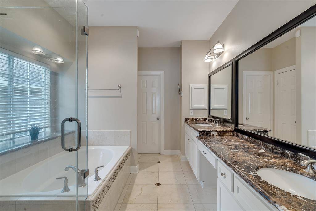 The primary bath with a double vanity, tub, and separate shower.