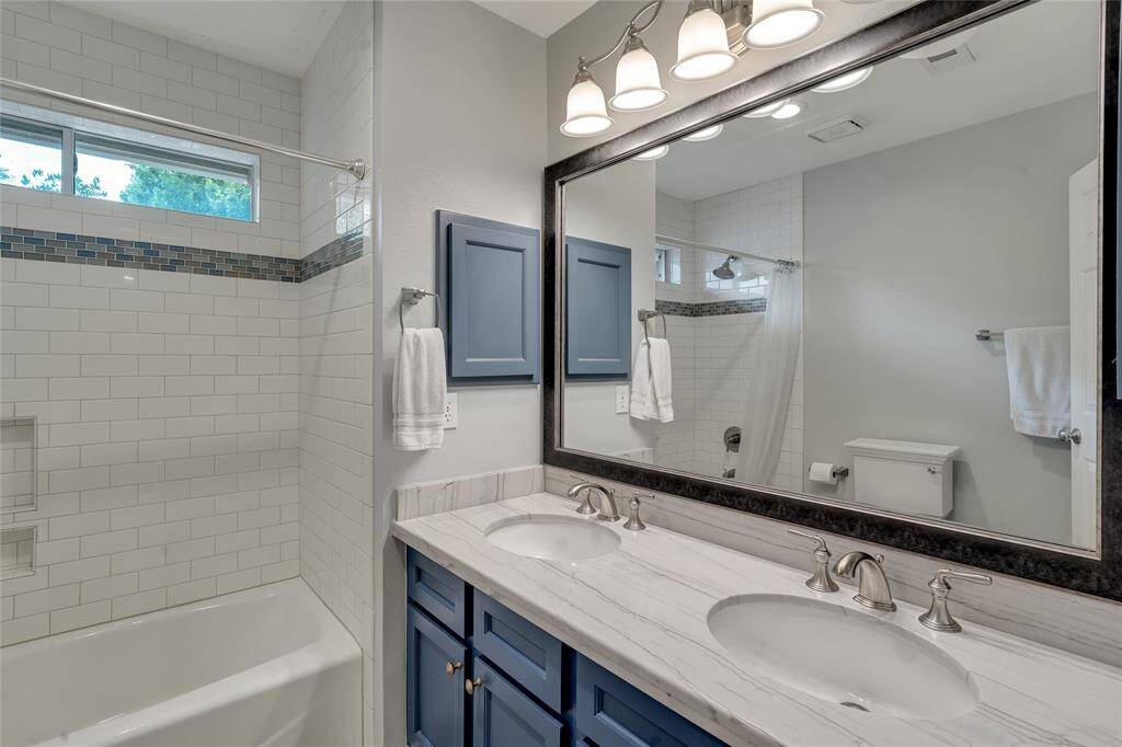 This bathroom is located between bedrooms 1 and 2. It was remodeled with quartzite countertops, subway tile, and 'wood-look' porcelain tiles.