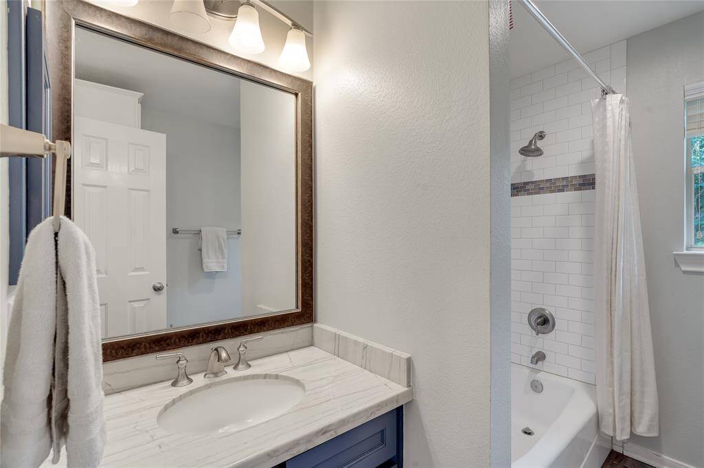 The second bathroom is located near the game room and bedroom 3. It has been remodeled with quartzite countertops, subway tile, and 'wood-look' porcelain tiles.