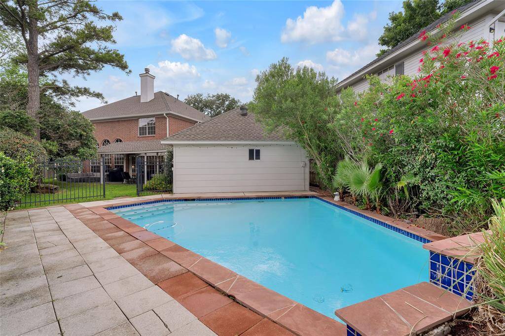 The swimming pool is fenced off with a security gate, separating it from the backyard.