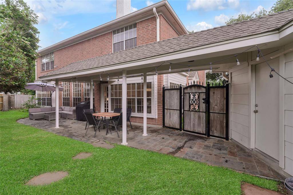 The patio is perfect for outdoor dining and living. The gate leads to the driveway and has a keypad lock. The door on the right leads to the garage.