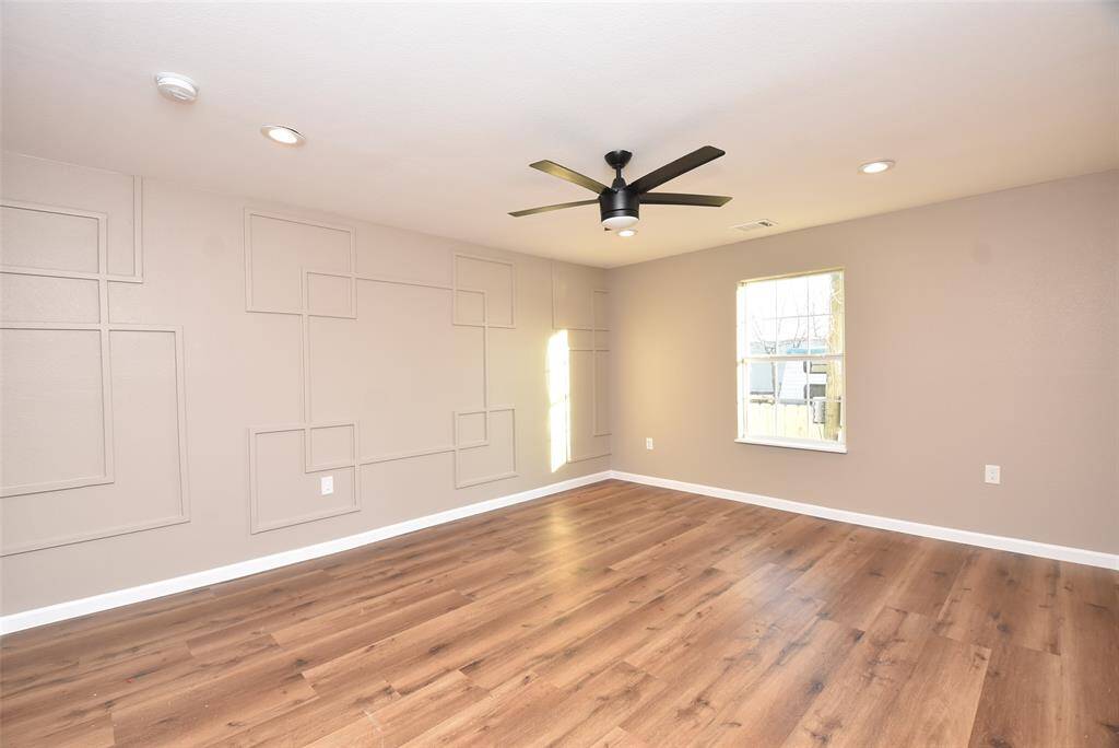 Spacious primary bedroom with ceiling fan, large window, and neutral paint!