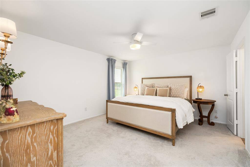 Primary bedroom with soft lighting, space to unwind and relaxing views of the backyard and pond.