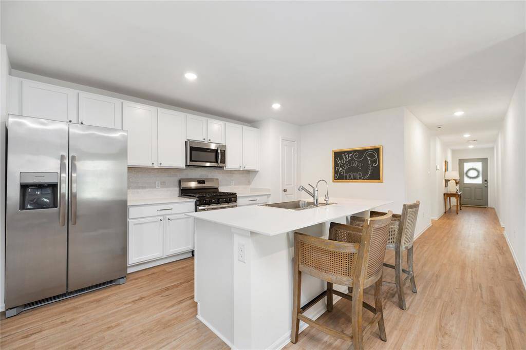 Stunning island kitchen with marble countertops, stainless steel appliances and white cabinetry and tile backsplash.