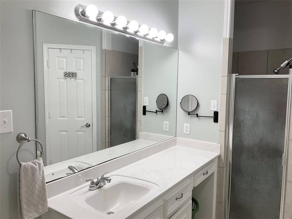 The primary bathroom is modernized with a sliding barn door, sink and fixtures. A door leads to a tiled bathtub area, and there's a glimpse into the adjoining primary bedroom. The color scheme is neutral and soothing.  The huge soaking tub and separate shower are delightful.  Don't miss the TWO closets in the bathroom!
