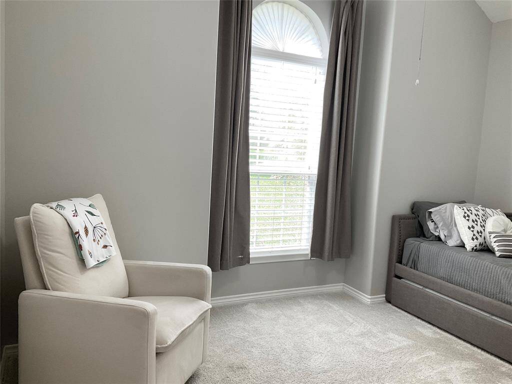 Bright and cozy bedroom with neutral walls and carpet, featuring a large window with elegant drapes, a high ceiling and ceiling fan.  This is an ideal guest room home, office or whatever your heart desires!