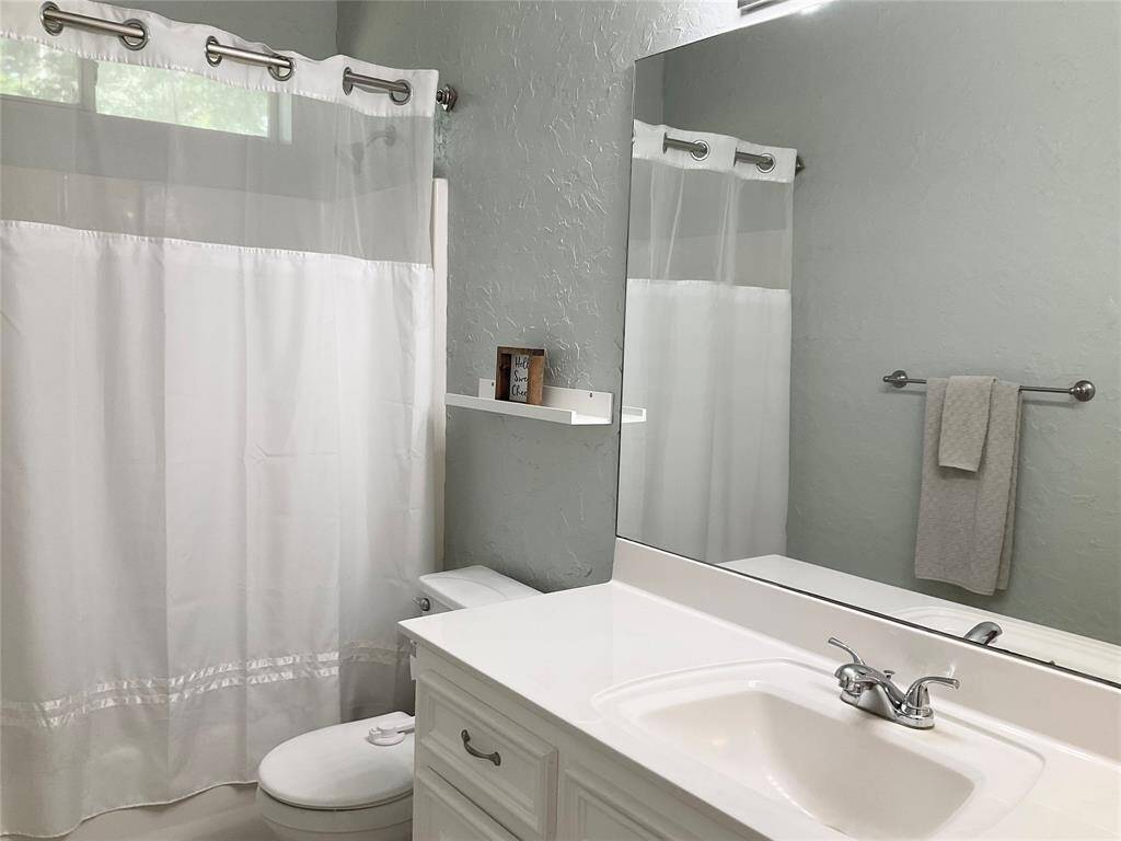 This bathroom features a clean, modern design with a white vanity, a large mirror, and a jub/shower combination which is ideal for any family member.