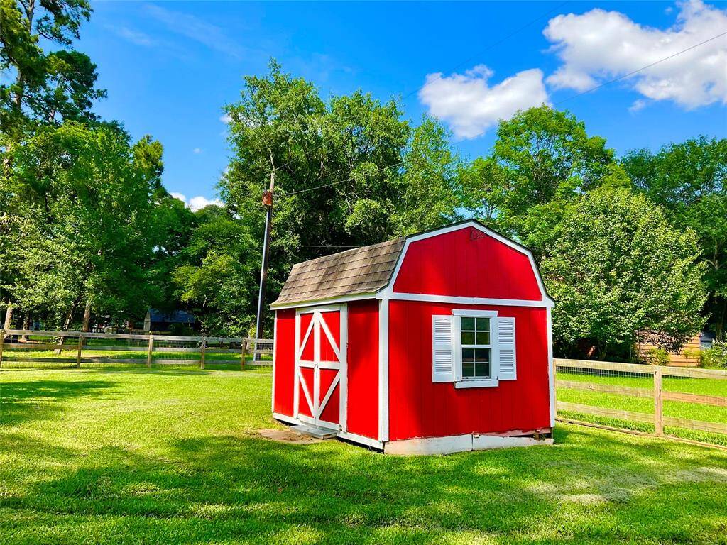 The property offers a charming red barn-style shed with white trim, set in a lush, green fenced yard. Surrounded by trees, it offers a picturesque, tranquil setting while being highly functional for your hearts desire.   The contents are excluded but this cute shed offers many uses for enjoyment.
