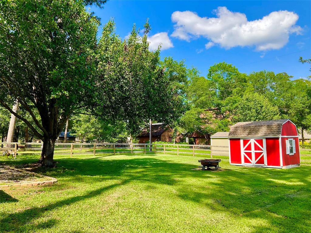 The property offers a charming red barn-style shed with white trim, set in a lush, green fenced yard. Surrounded by trees, it offers a picturesque, tranquil setting while being highly functional for your hearts desire.   The contents are excluded but this cute shed offers many uses for enjoyment.