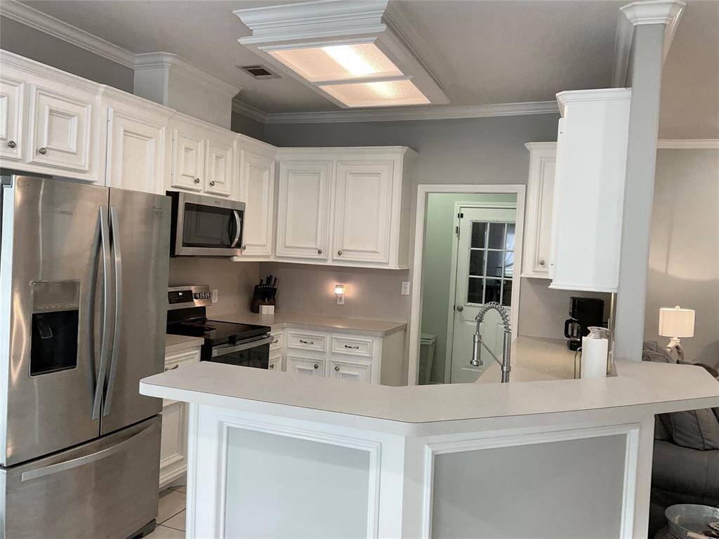 This kitchen features modern stainless steel appliances, white cabinetry, and a sleek countertop. It offers a cozy layout with ample storage and a contemporary, welcoming feel.  The floor plan is ideal and flows conveniently.