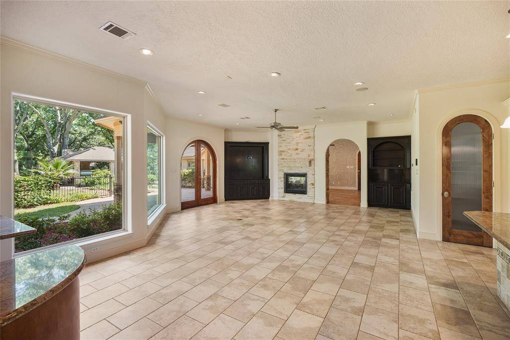 Stunning living room framed by elegant custom archways, a grand stone fireplace, and expansive windows that flood the space with natural light - timeless design meets elevated comfort