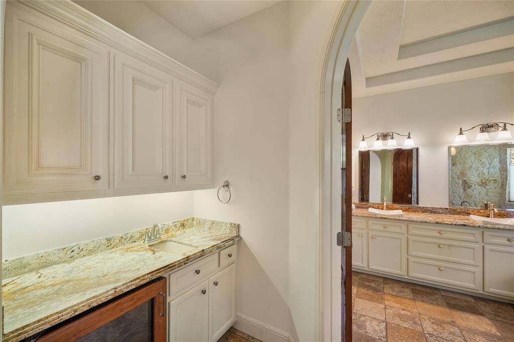 Elegant coffee bar in the primary suite, complete with custom cabinetry, fridge, and stylish finishes - designed for convenience and indulgence without leaving your retreat