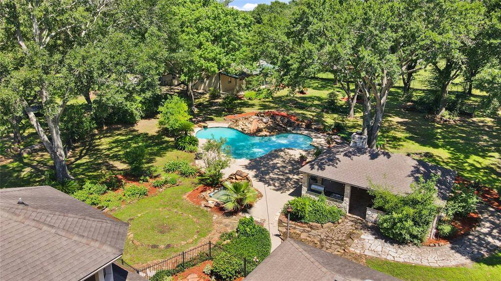 Aerial view of the expansive backyard, featuring the luxurious pool, inviting outdoor spaces, and lush landscaping