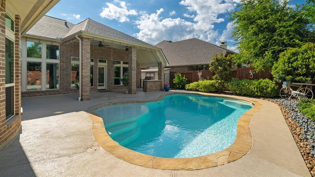 Discover your private oasis with this charming backyard featuring a freeform pool and neat patio. The brick exterior and large windows offer seamless indoor-outdoor living, while lush landscaping enhances privacy, perfect for relaxation and entertaining.